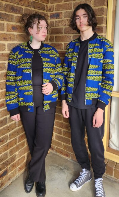 Boy and girl wearing Bomber Jacket in blue and green geometric shape print design